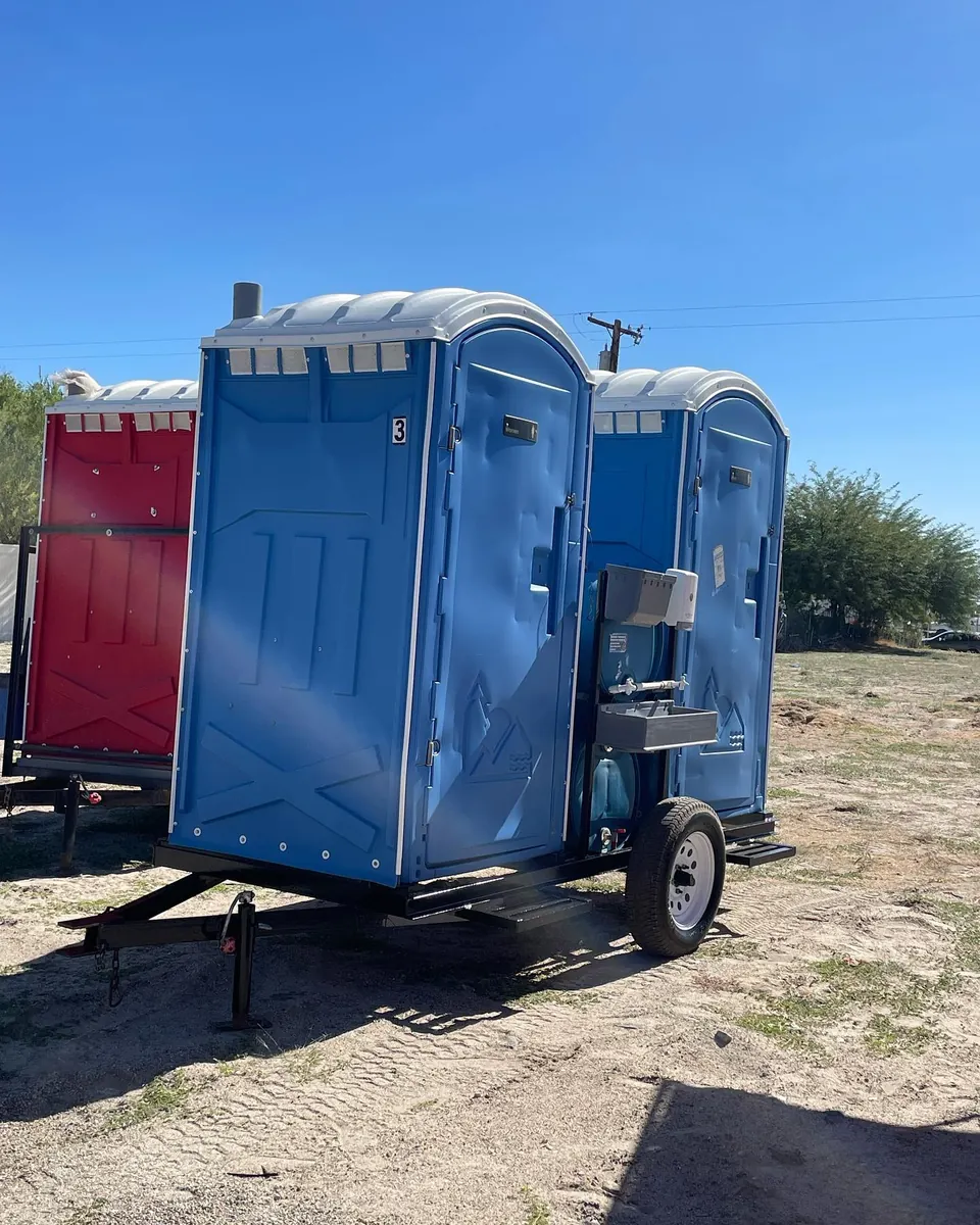 Blue portable toilets beside a service vehicle